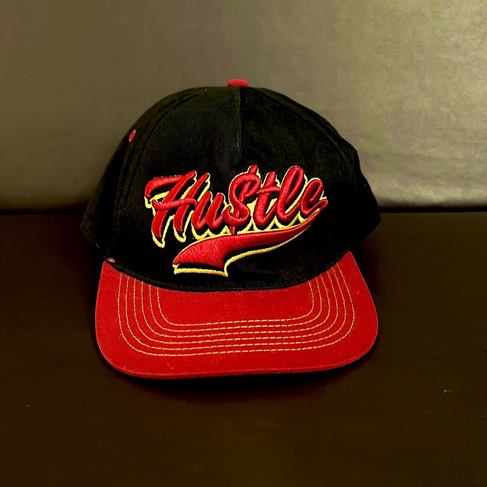 A hat the color is red, yellow and black on it have roses and they got graffiti